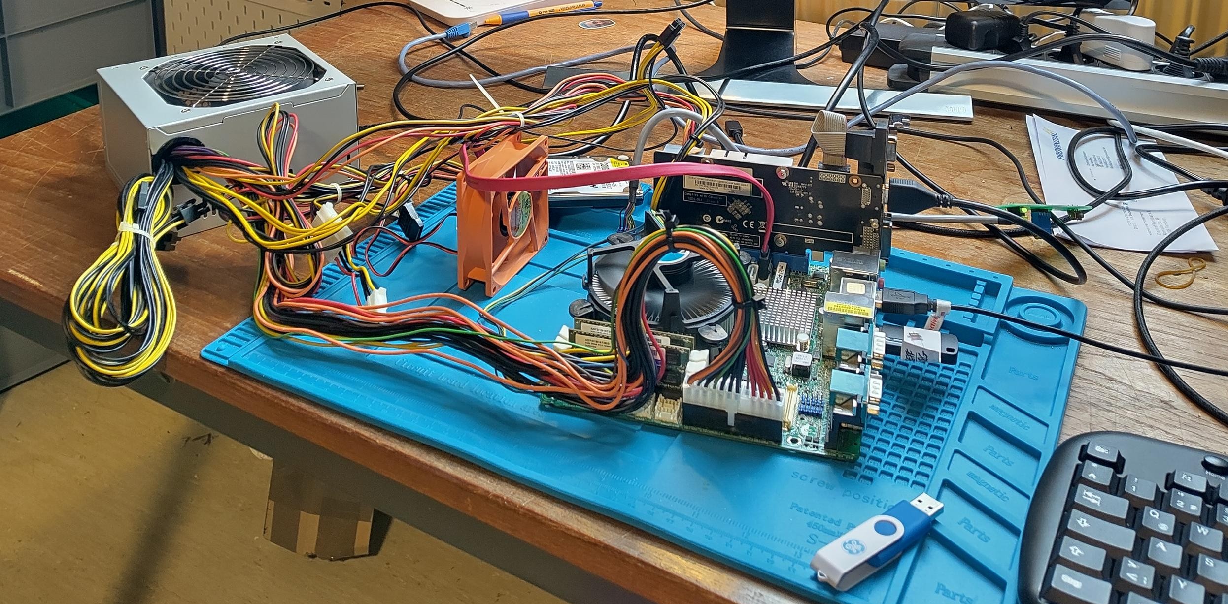 Auf einem Schreibtisch stehen verschiedene verbundene Elektronik Bauteile die an einem externen Monitor angeschlossen sind