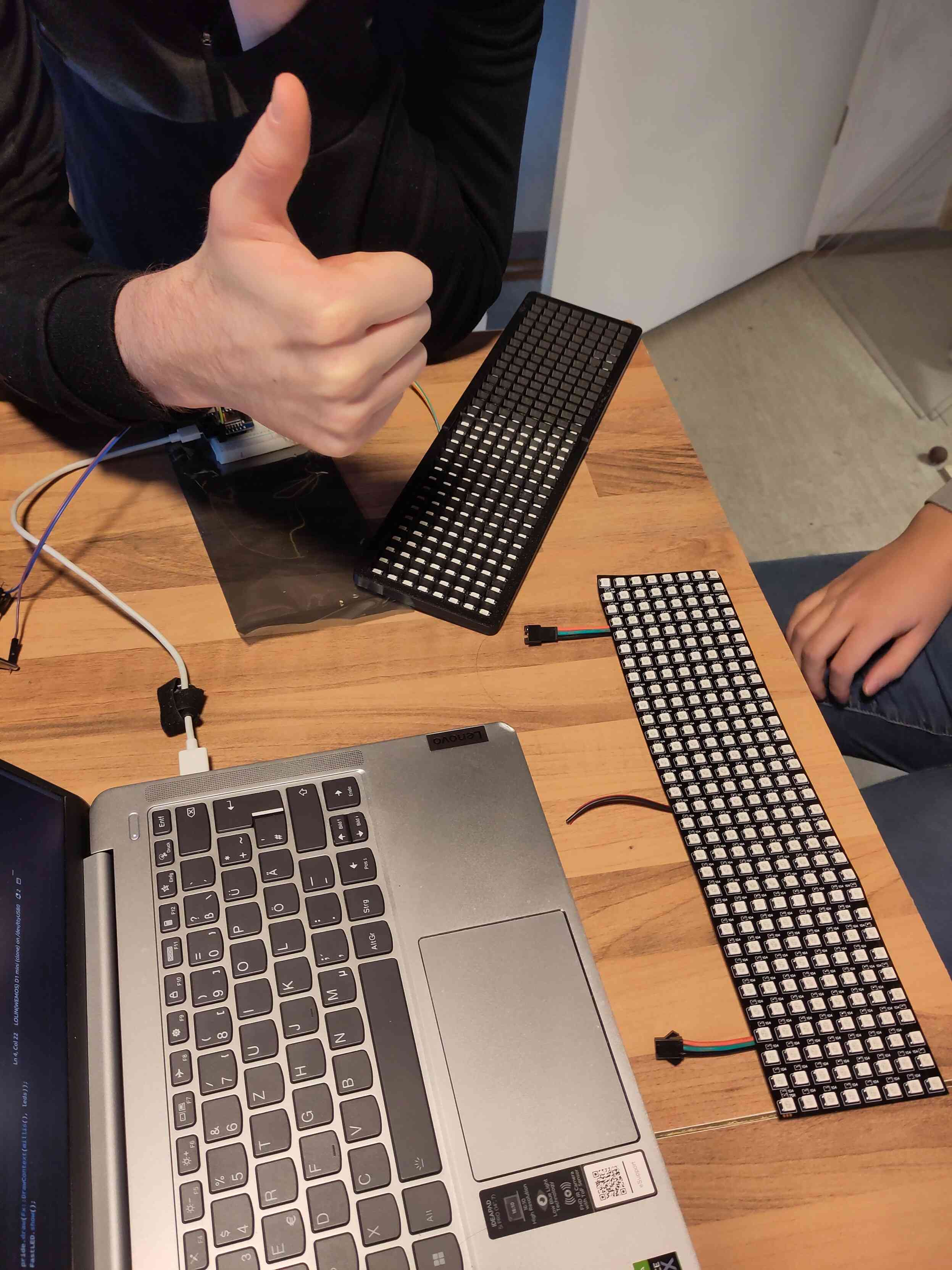 Zweimal 32*8 Led Matrix liegen auf einem Tisch. Die eine ist abgedeckt von einer Abdeckung. Außerdem steht da noch ein Laptop und ein Daumen wi d ausgestreckt.